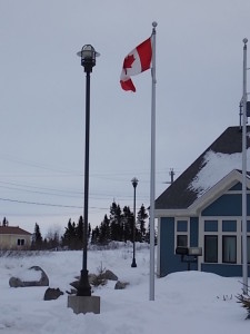 Maple Leaf Flag outside new RCMP (police) building in Innu village of Sheshatshiu. The Innu word on the RCMP sign means  `The house of the people who grab you.`  Photo Anthony Jenkinson.